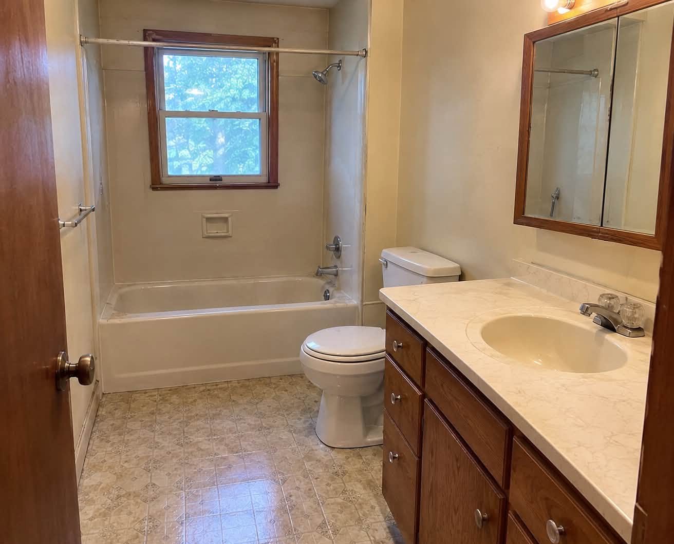 Before: dated bathroom with tub and vinyl floor
